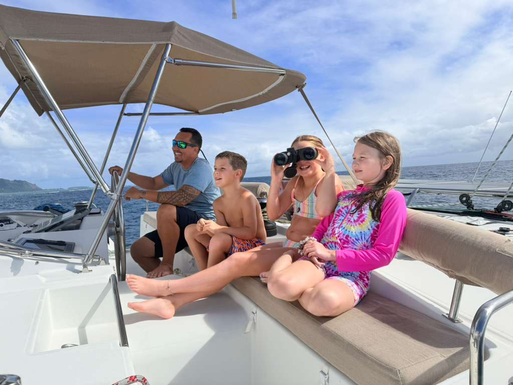Enfants admirant la vue près du capitaine à la barre du catamaran