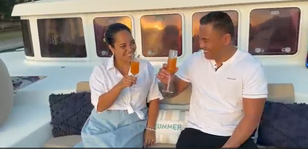 Un couple trinque à bord de TUATAU V dans la lumière dorée de l’après-midi